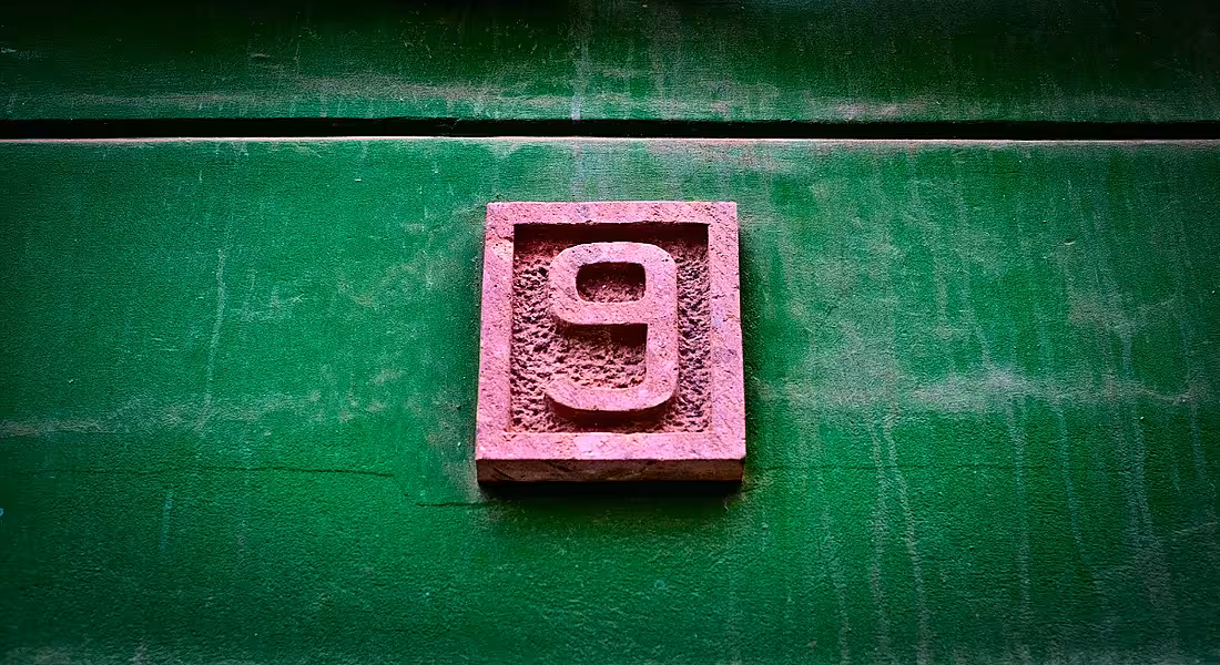 A pink number nine on a vivid green wall.