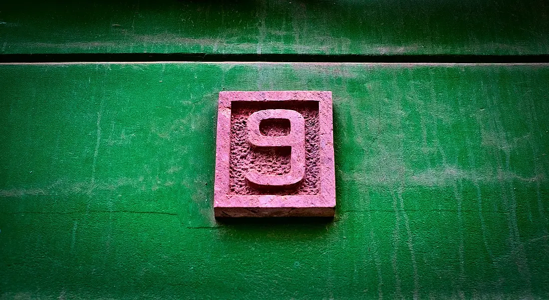 A pink number nine on a vivid green wall.