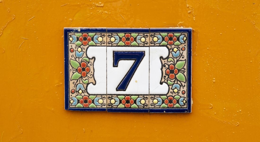Tiled number seven on a bright orange wall.