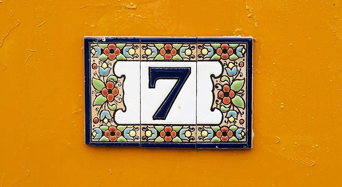 Tiled number seven on a bright orange wall.