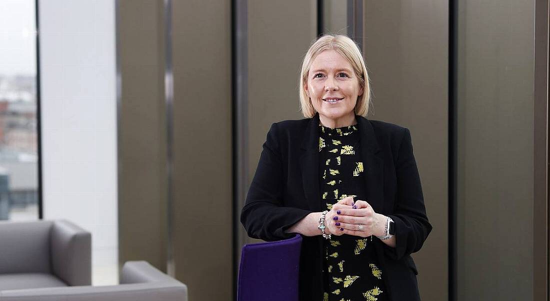 Tracey Sullivan of Grant Thornton is smiling into the camera in a corporate office setting.