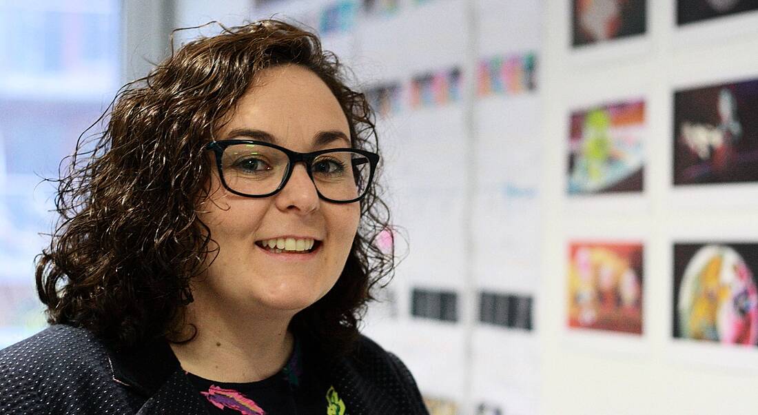 Niamh Herrity is smiling into the camera in front of a wall showcasing animations.