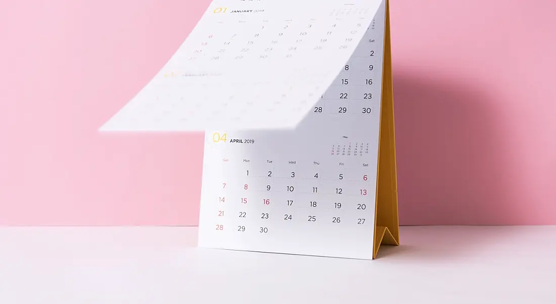 Paper spiral calendar on a pink background.