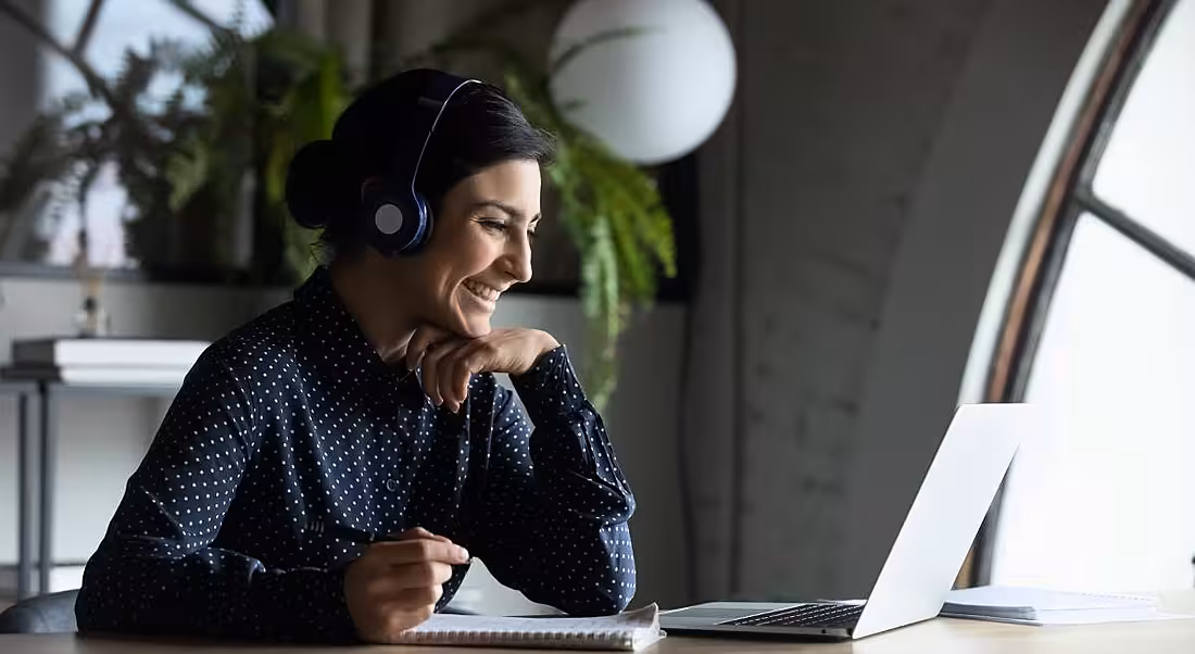 A woman is taking part in virtual training on her laptop at home.