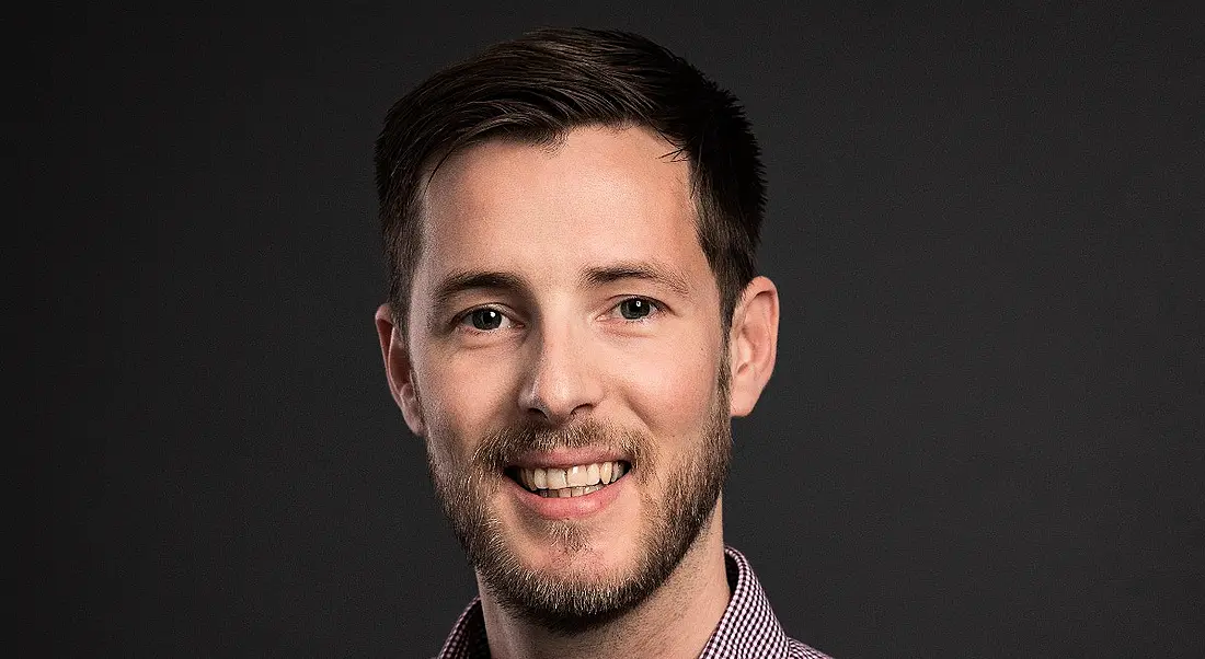 A headshot of a young man with dark hair smiling at the camera. He is Derek Hughes from BMS.