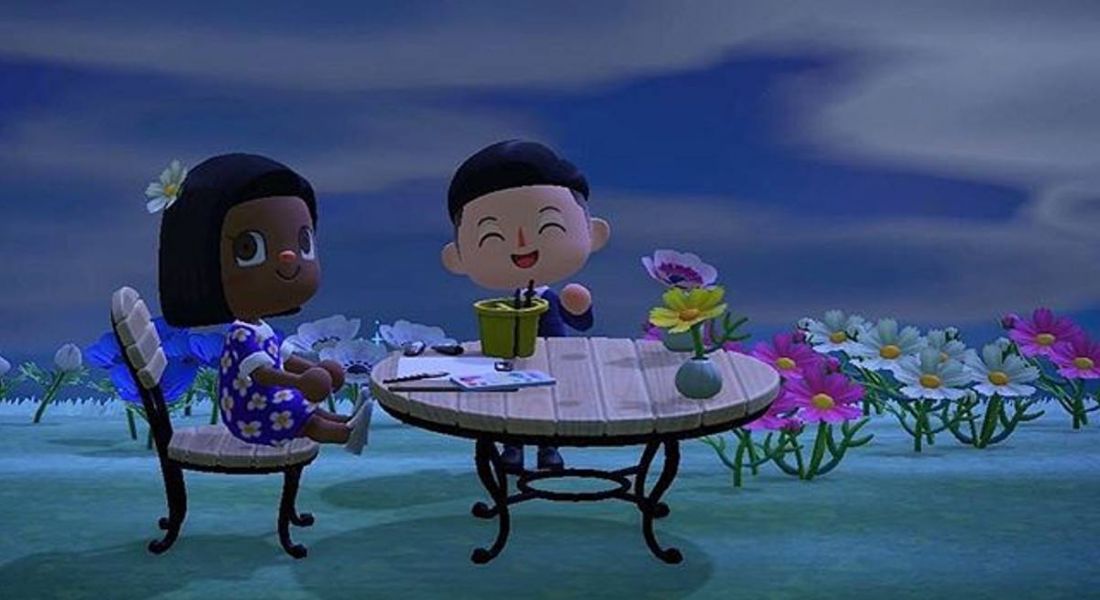 Sheree Atcheson's character in the Animal Crossing game is sitting at a table with another character at nighttime.