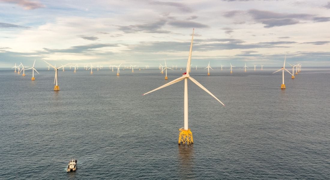 Wind turbines are dotted across a section of the ocean at a windfarm.