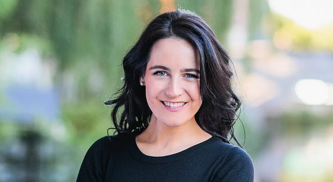 Sarah Reynolds, a woman with dark hair against an out-of-focus outdoor background.