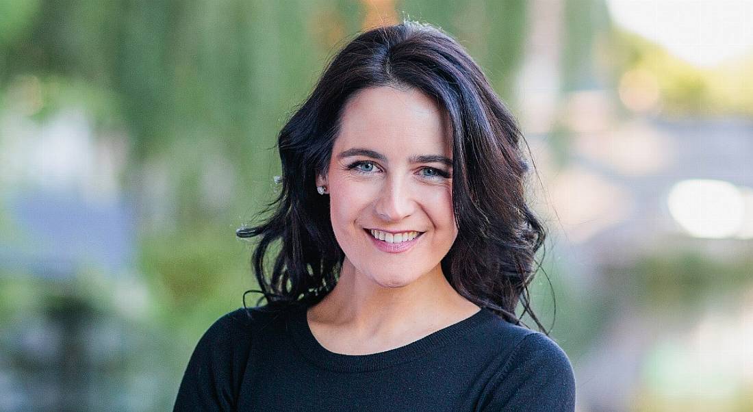 Sarah Reynolds, a woman with dark hair against an out-of-focus outdoor background.