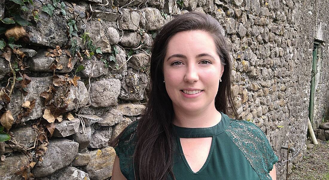 Mary Seery, in software development at Fidelity Investments, is standing outside in front of a grey brick wall, smiling into the camera.