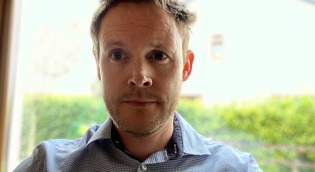 Niall Colreavy, software architect at Fidelity Investments, is smiling into the camera in front of a window.