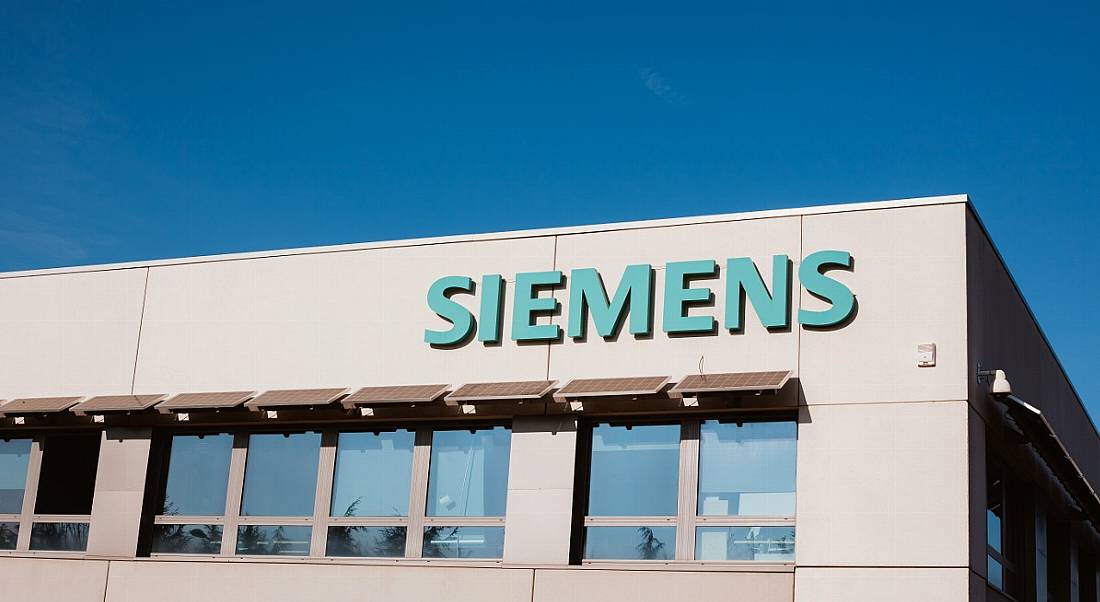 Siemens company logo on a grey building against a bright blue sky.