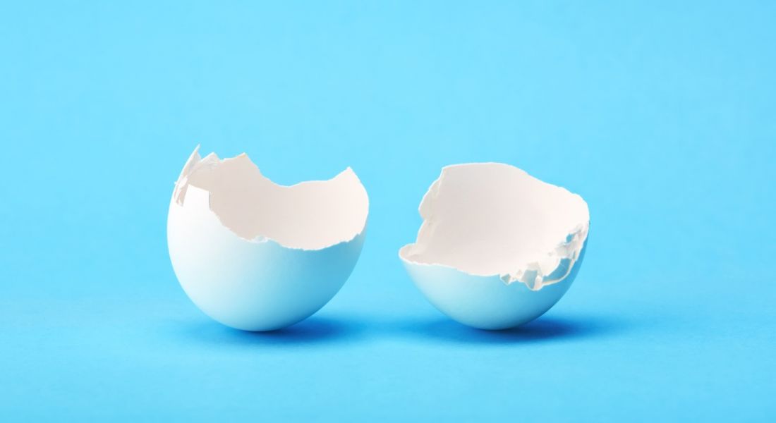 One white broken egg shell on blue background.