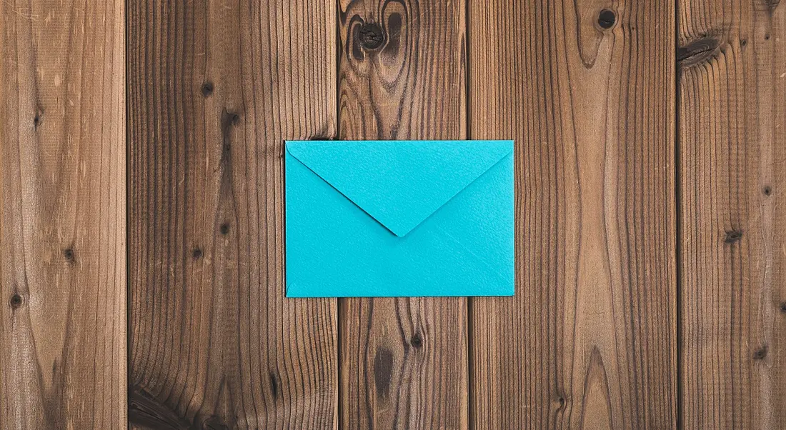 A bright blue envelope on a wooden background, symbolising a resignation letter.