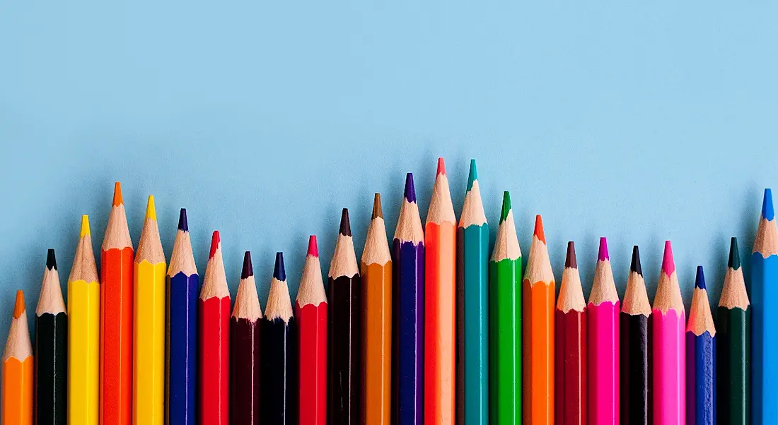 Different coloured pencils on blue paper, symbolising diversity and inclusion.