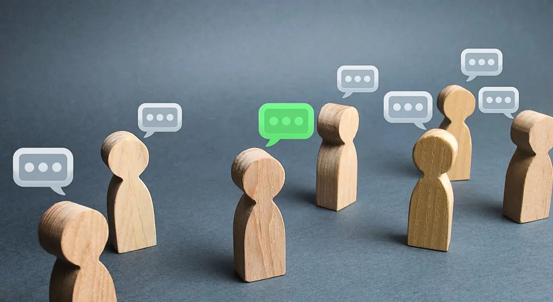 Small wooden figures have speech bubbles over their heads on a grey background.