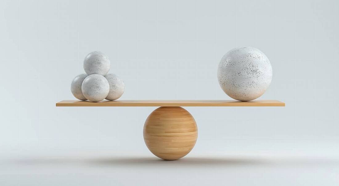 A wooden board bearing three stone balls on one side and one large ball on the other is perfectly balance atop a wooden sphere.