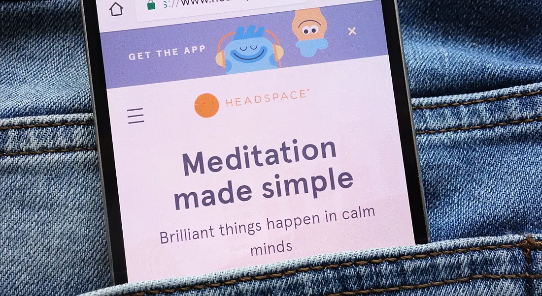 A mobile phone in a jeans pocket open on the Headspace homepage.