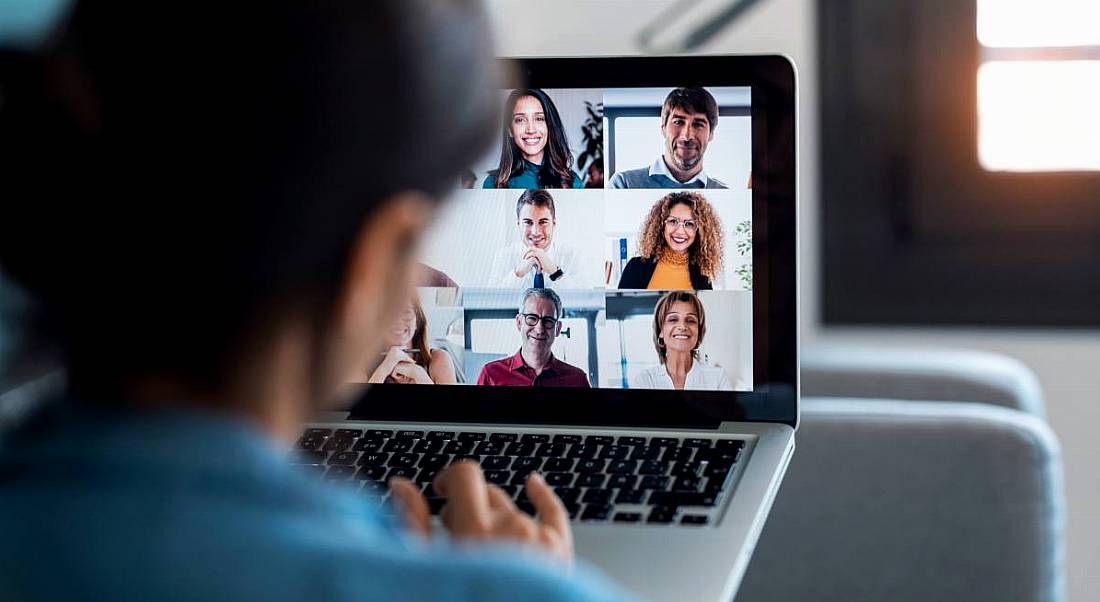 Businesswoman speaking on video call with diverse colleagues on her laptop from home.