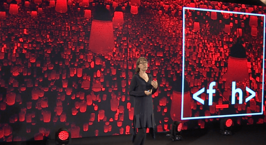 Future Human founder Ann O’Dea stands in front of a large screen bearing the Future Human logo.