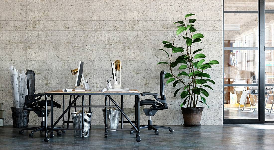 Two desks with large screens up against each other in a very spacious, industrial-style office.