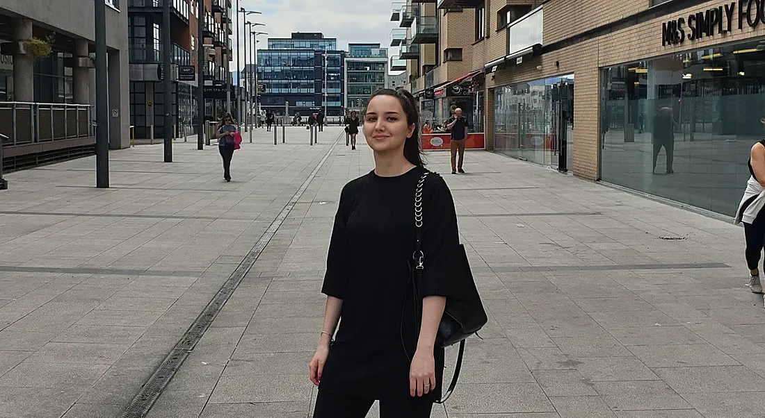 Iva Simon Bubalo is standing on a city street and smiling into the camera.