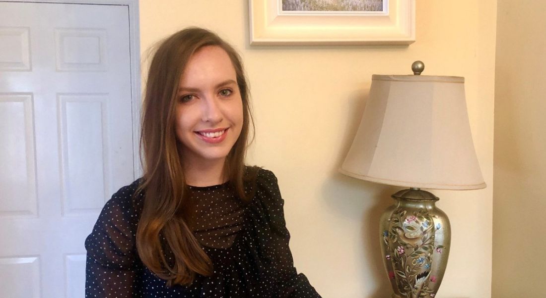 Laura Sinnott, a data scientist at Aon, is standing in a living room and smiling into the camera.