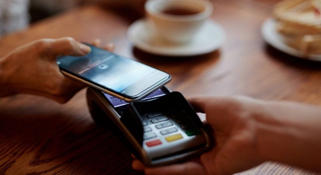 Person holding their phone at a terminal to pay for their coffee.