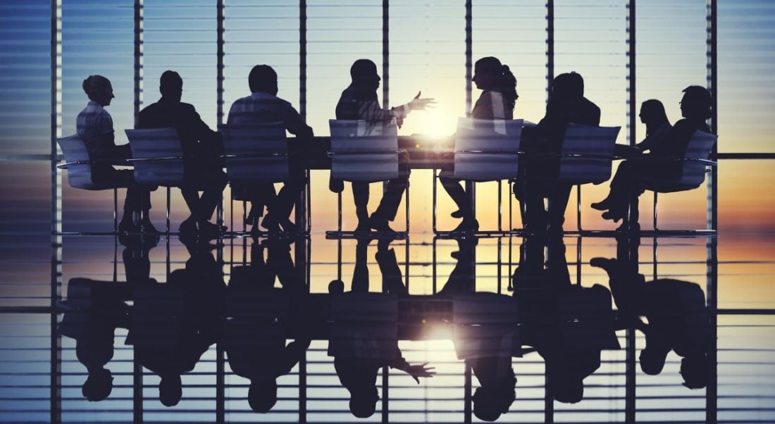 Silhouettes of board members meeting in a room at sunset.