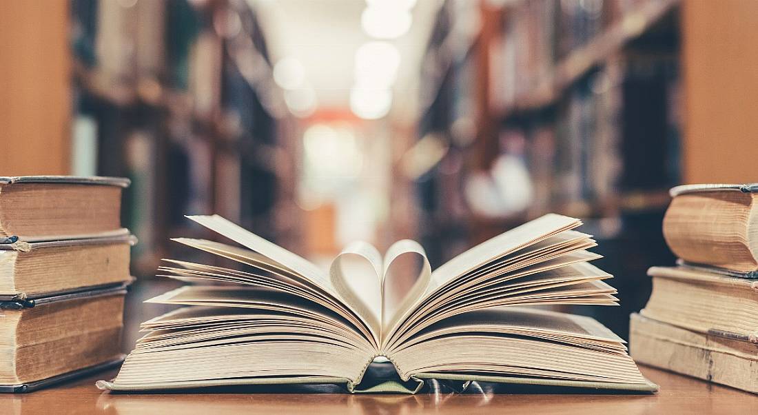 Book on a table in a library, with two pages forming the shape of a heart.