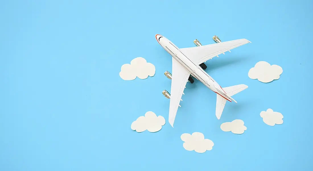 Toy airplane and white clouds on blue background.