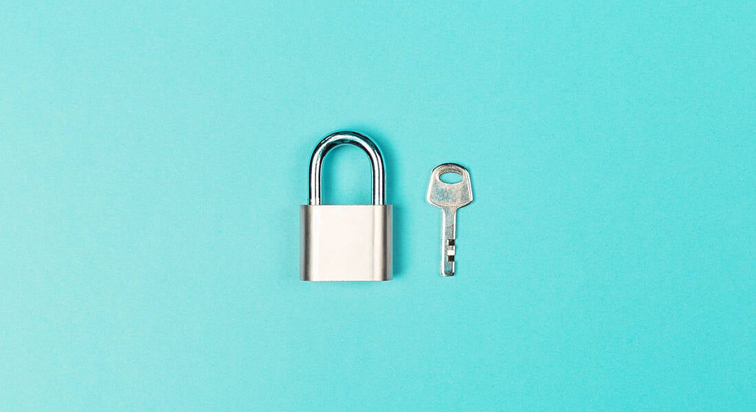 A small silver padlock and key sit against a blue background.