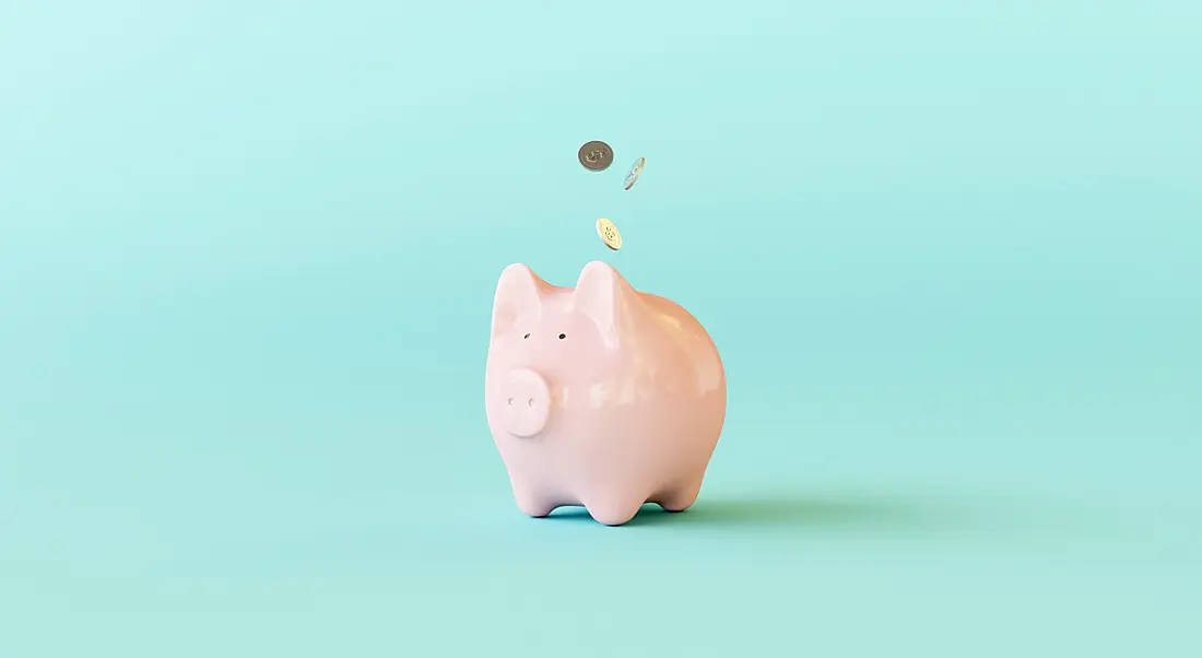 Pink piggy bank against a turquoise background.