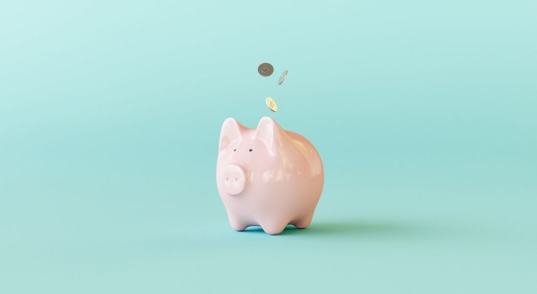 Pink piggy bank against a turquoise background.