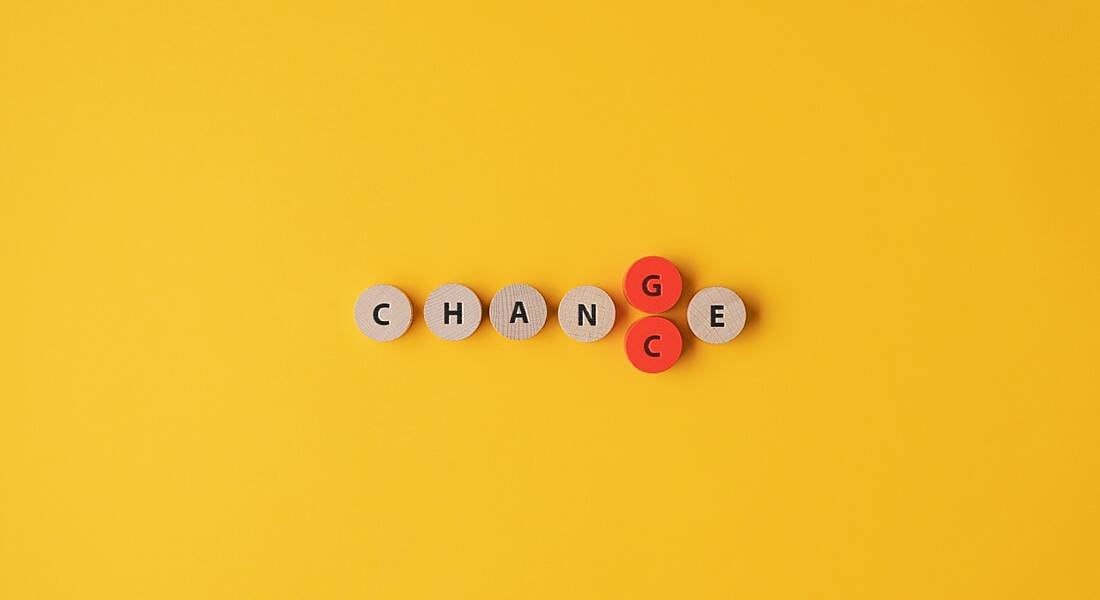 The word 'change' is spelled out on small wooden circles that are placed against a yellow background. The circle for the letter G is coloured in red and is being replaced by another circle that features the letter C, effectively switching 'change' to 'chance'.