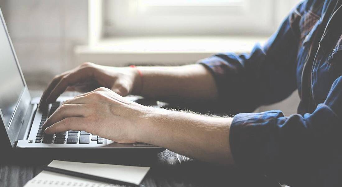 Close-up image of a man working on his laptop at home.