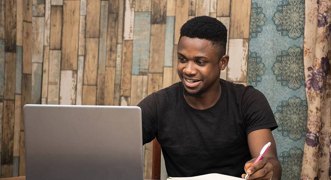 A young man is studying at home using his laptop.