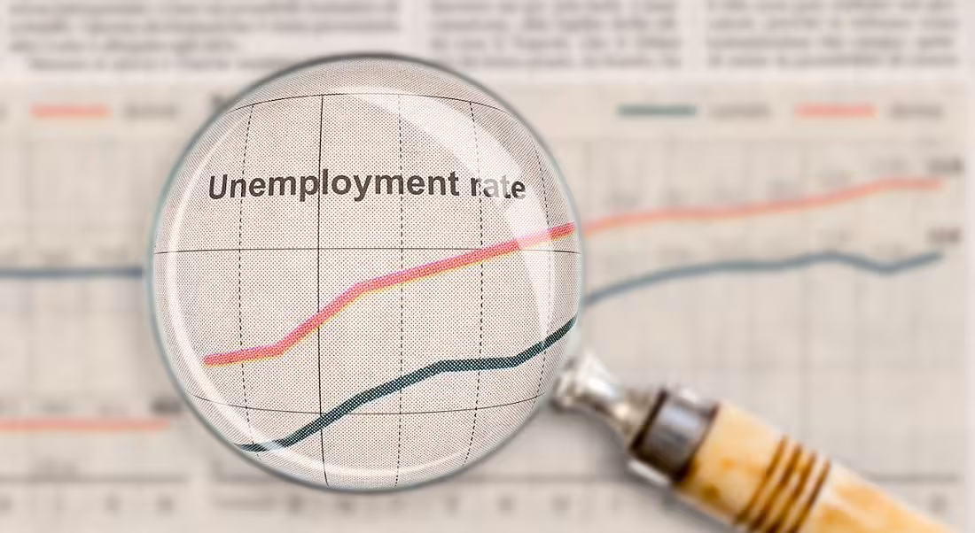A magnifying glass is looking at unemployment rates on a document.