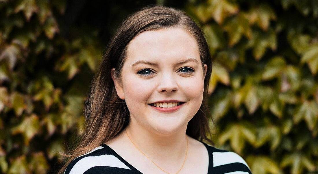 Edel Browne, who completed the Accenture graduate programme, is standing outside in front of foliage and smiling into the camera.