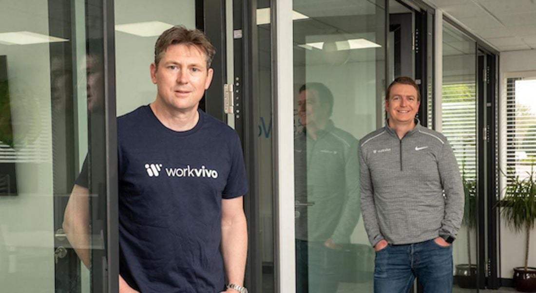 Two men in Workvivo shirts stand in a bright office space.