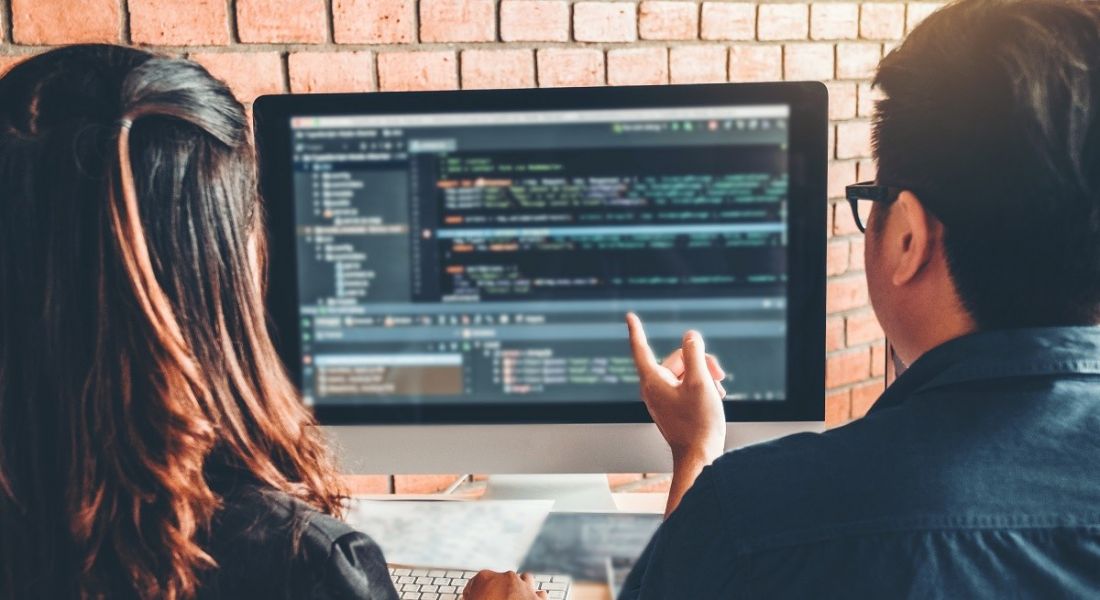 A man and a woman sit at a computer learning how to code.