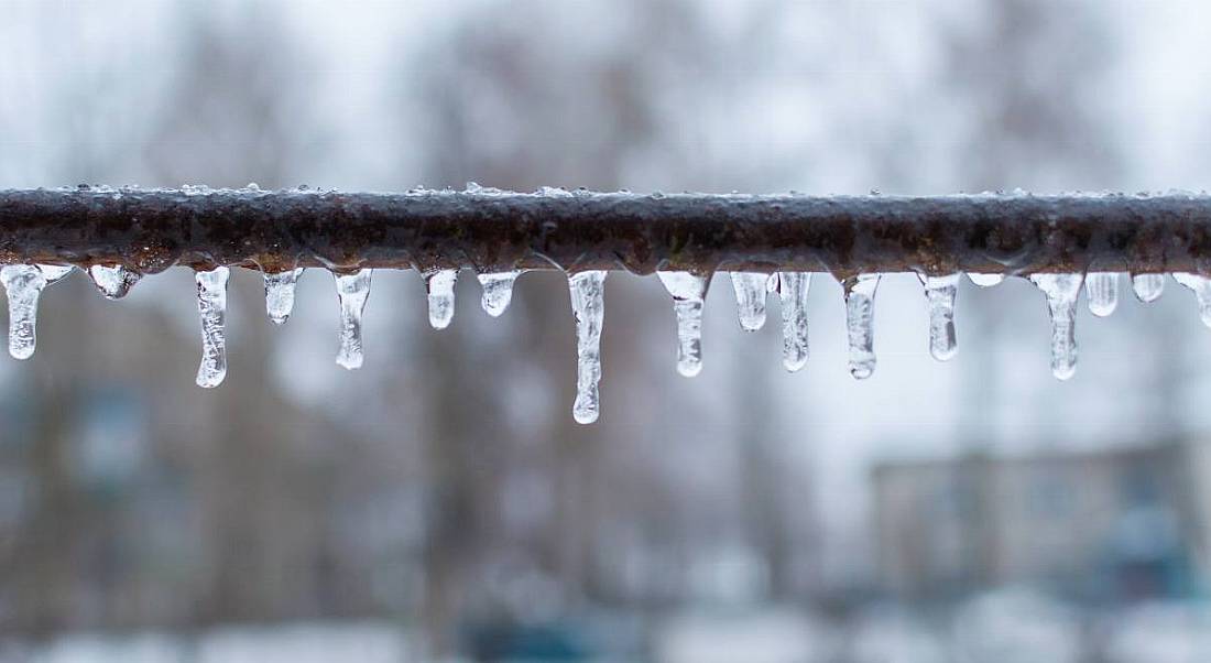 Icicles on a metal crossbar in a cold winter outdoor setting.