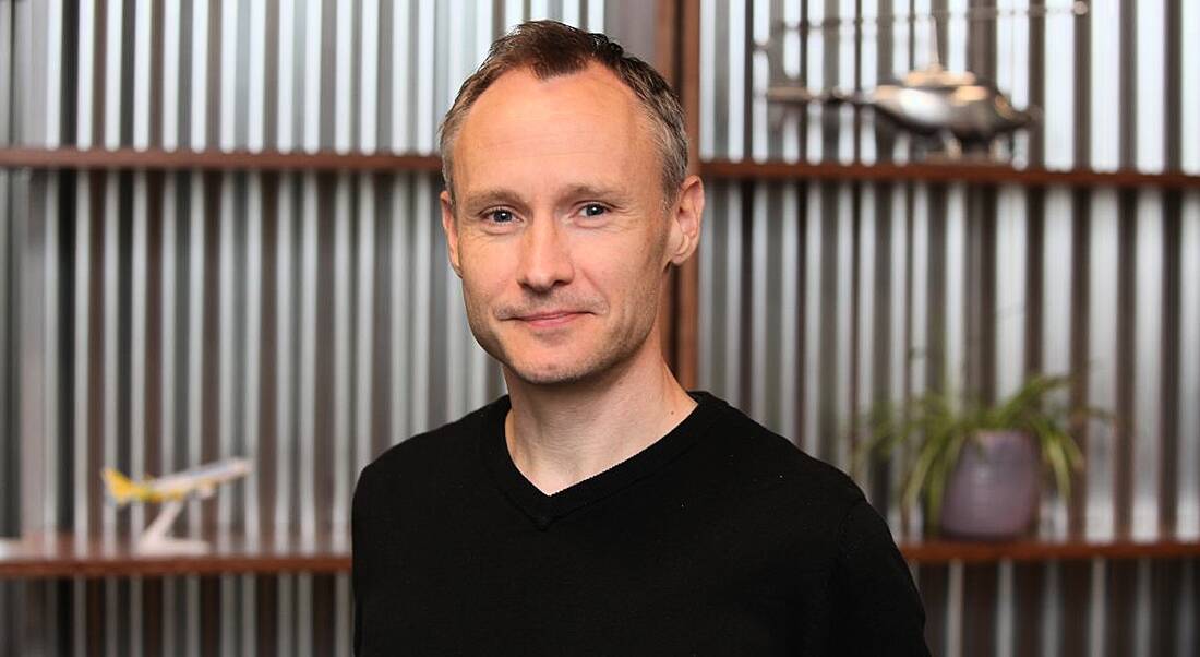 Breffni Murdoch of Viasat Ireland is smiling into the camera, standing in front of a contemporary office backdrop.