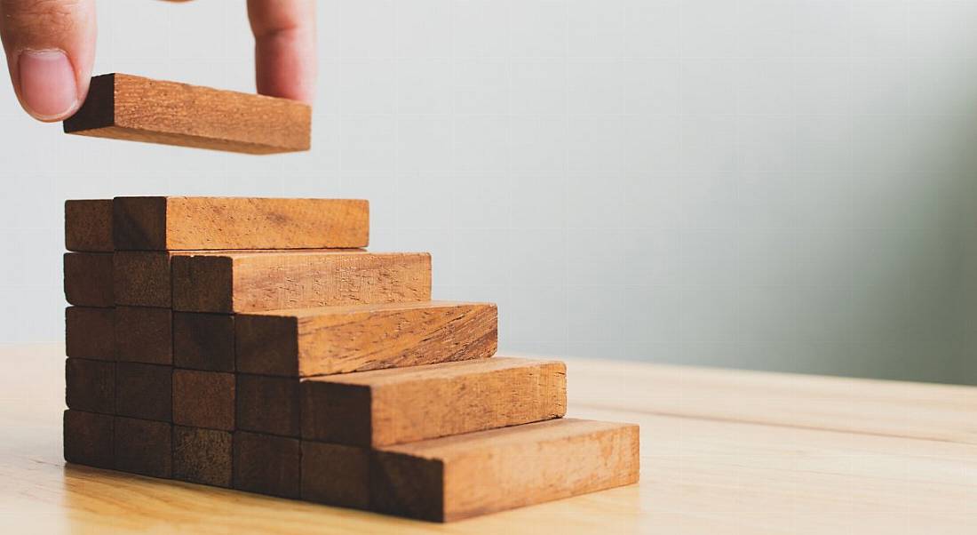 Hand arranging wood block stacking as steps.