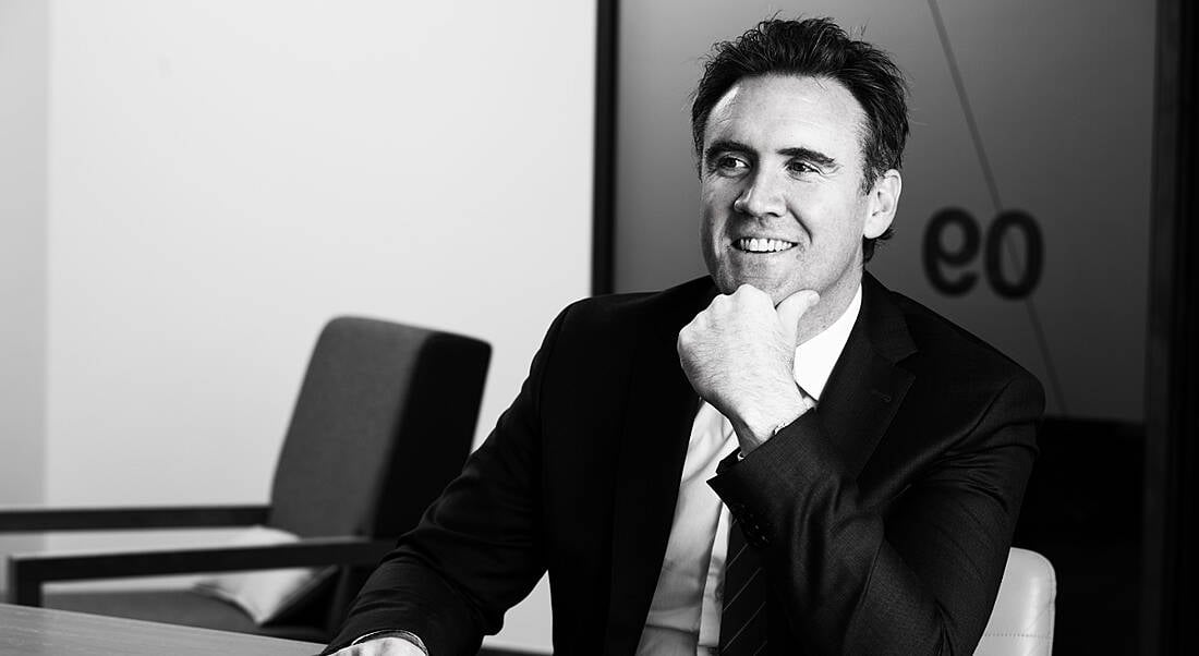 Black and white photo of Danny Buckley of EY in a suit, smiling at someone off camera.