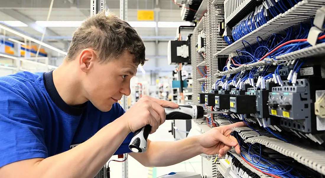 A young man is working on a fuse box.