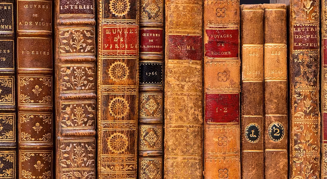 Old-fashioned books lined up on a shelf.