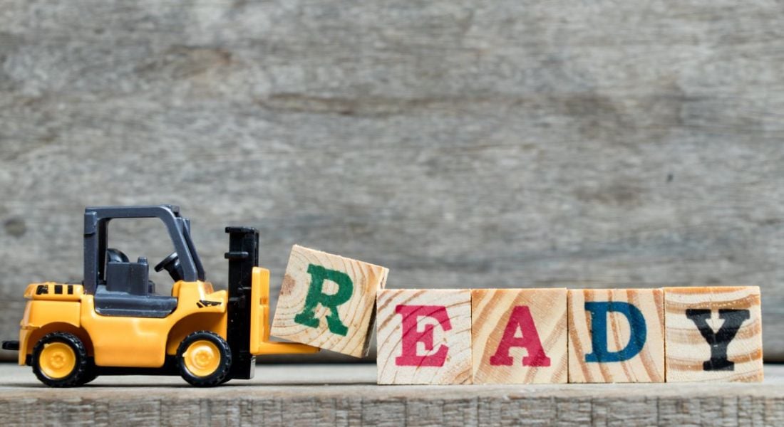 Yellow plastic forklift adding the letter R to complete word 'ready' on wooden blocks.