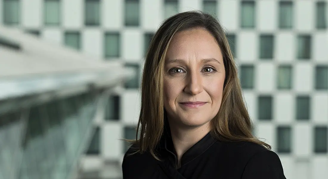 Sinead Barry is standing in a modern office space in Accenture and smiling into the camera.