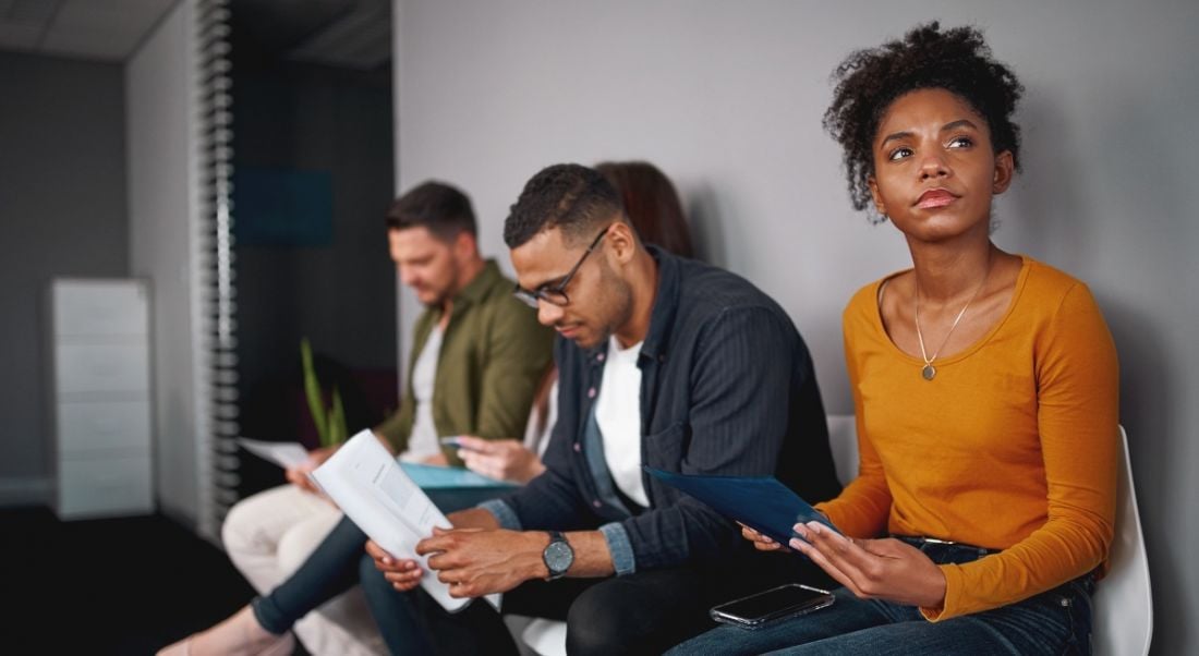 Three people sitting in a line, waiting to be called for interview.